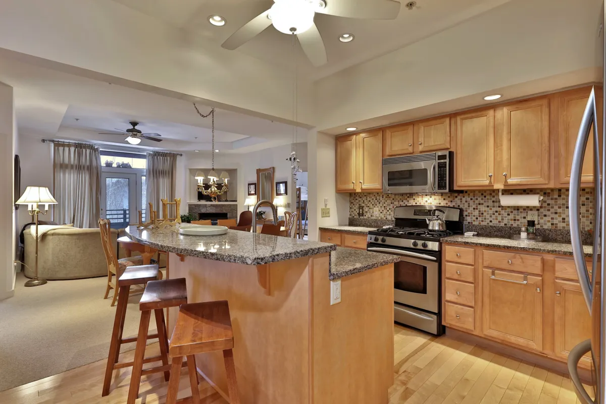 This image showcases the open-concept layout that seamlessly brings together the kitchen, dining area, and living room. Granite countertops, a kitchen island with stainless steel appliances, and views toward the living space hint at warm gatherings. The overall setup radiates a welcoming and cozy atmosphere, perfect for family and group activities.