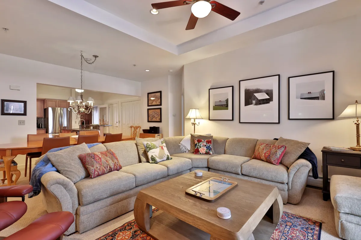The image showcases a welcoming living room with a comfortable, plush sofa, a stylish wooden coffee table, tasteful artwork adorning the walls, and warm lighting from elegant lamps. The scene exudes a cozy, inviting atmosphere perfect for relaxation and gathering with friends or family after a day on the slopes.